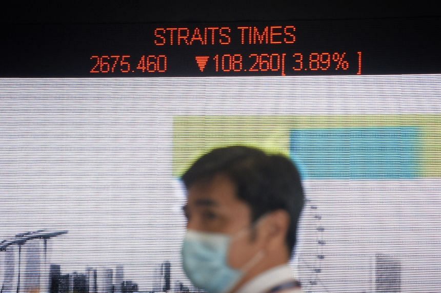 A security guard donning a mask is seen in front of an electronic stock board showing the Straits Times Index at The SGX Centre on March 12, 2020.